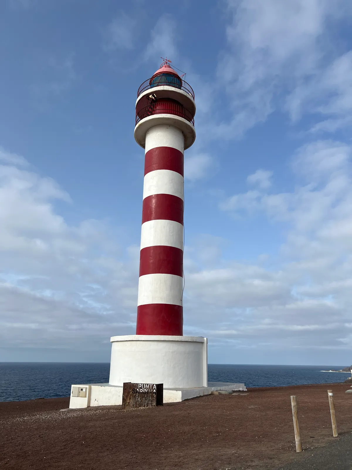 The red-and-white striped Punta Sardina lighthouse by the sea on the Gáldar coast