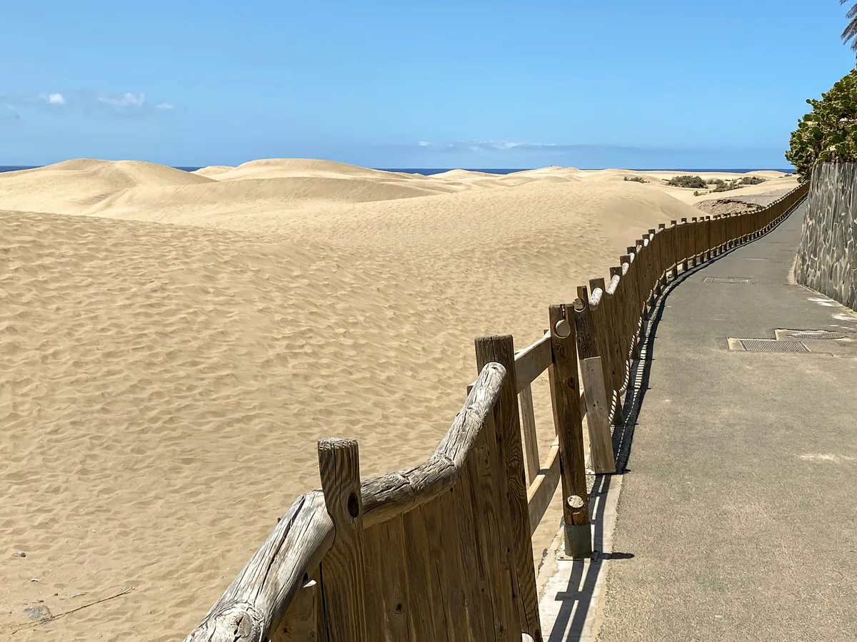 Paseo junto a las dunas de Maspalomas, separado de la arena por una valla de madera