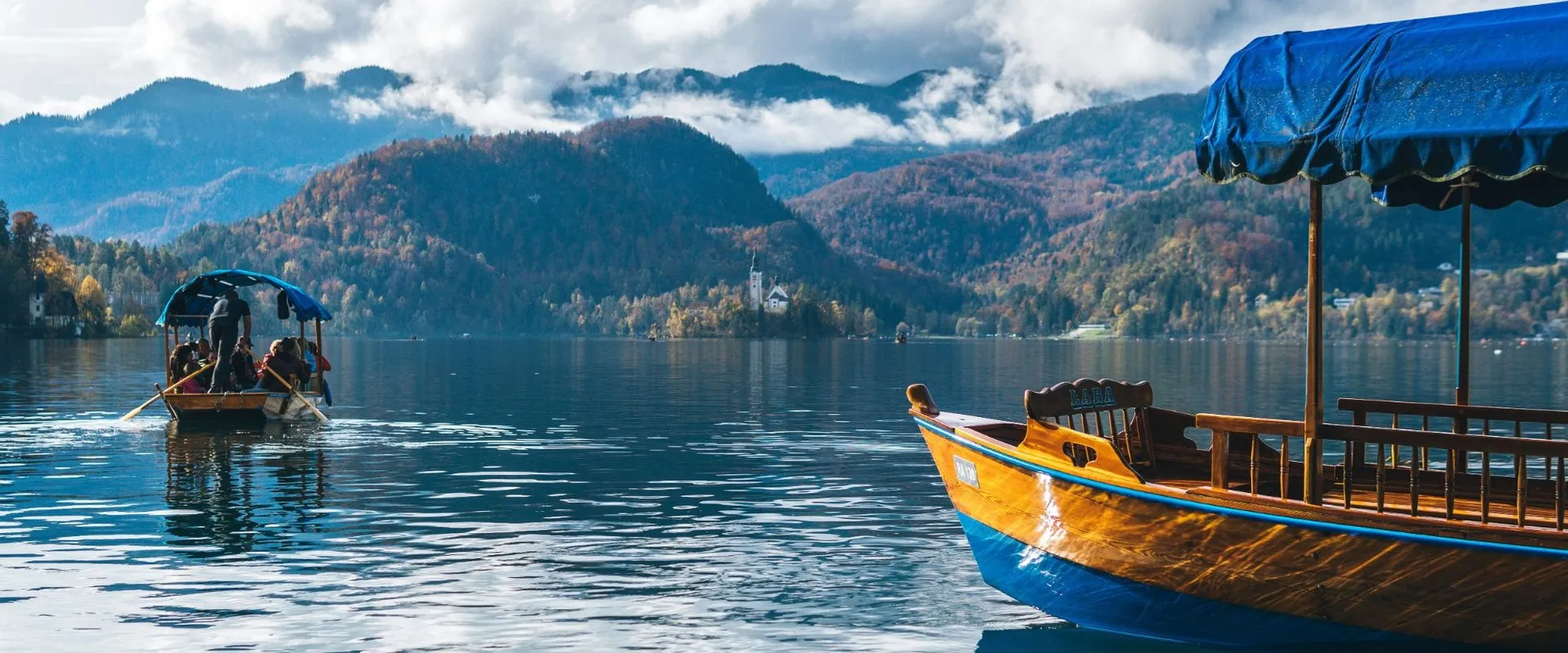 Traditional wooden boats on Lake Bled, Slovenia, with the island church in the distance
