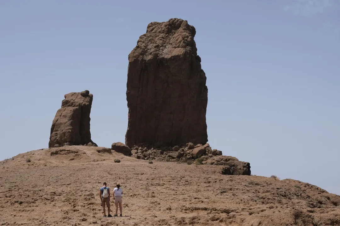 Two hikers standing before Roque Nublo, high in the mountains of Gran Canaria